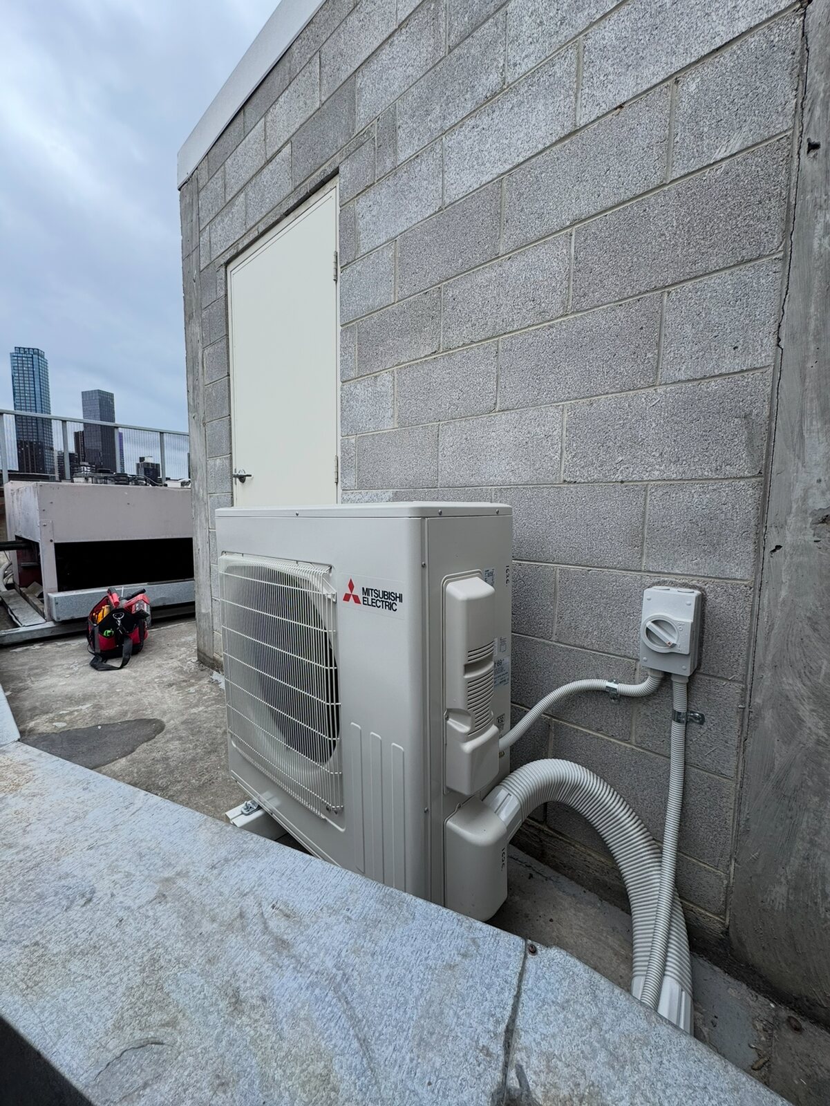 Rooftop HVAC unit with electrical isolator and Melbourne buildings behind